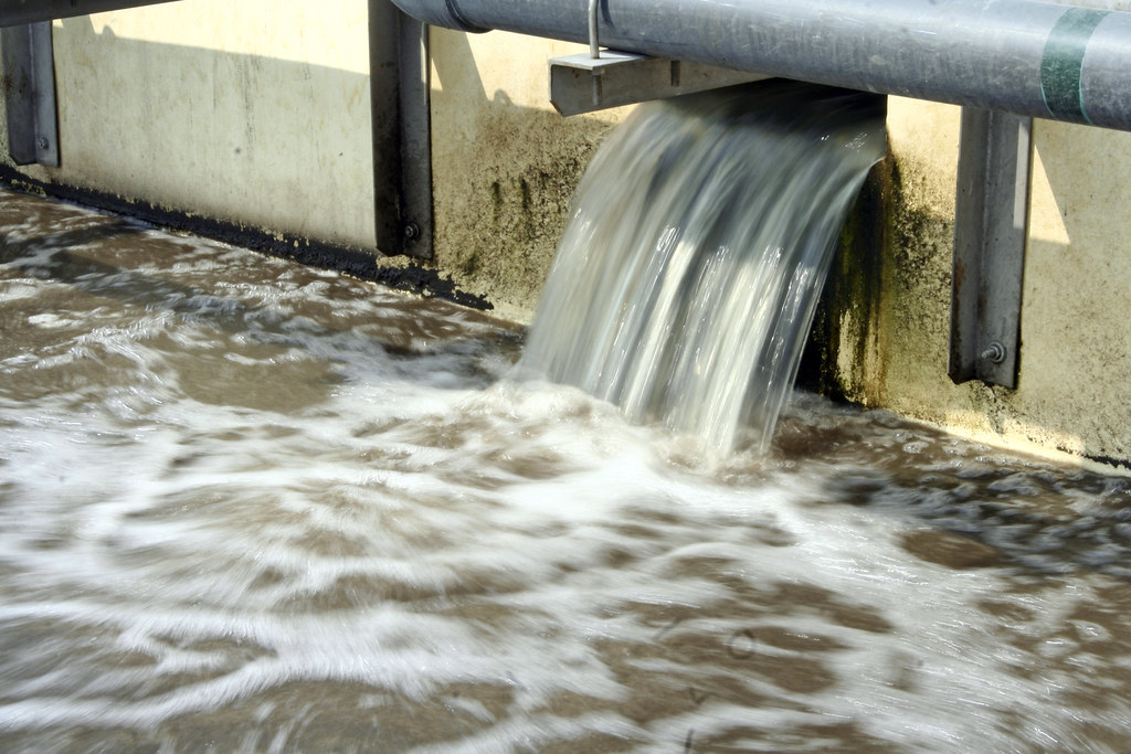 A stream of water from a cooling tower going down into the sewer