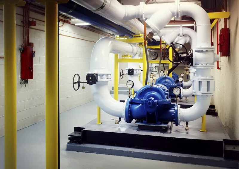 A white and blue closed loop system in a dim mechanical room