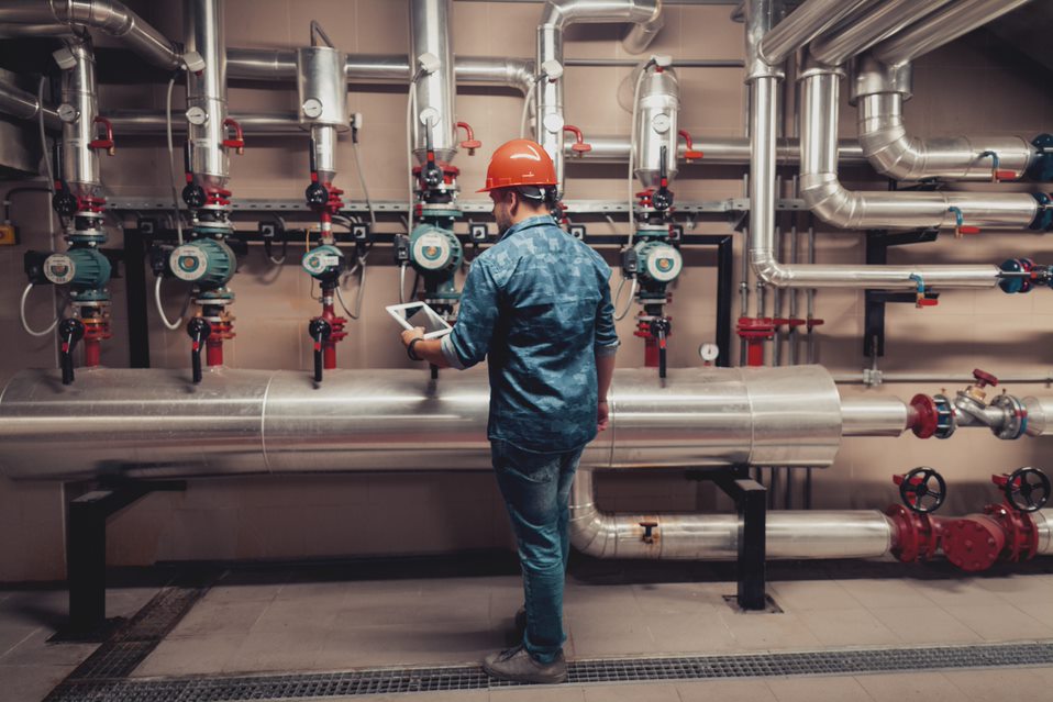 Man in a boiler room inspecting the boiler tubing